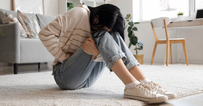 Young woman suffering from severe abdominal pain at home