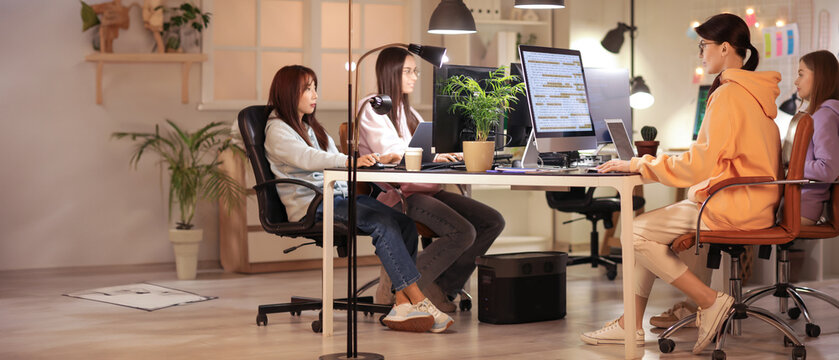 Team of female programmers working in office at night