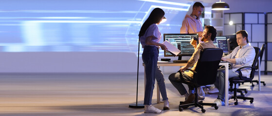 Male programmer with coffee cup and his team working in office at night