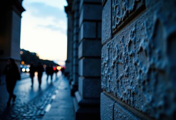 Textured stone wall with blurred pedestrians in the background at dusk