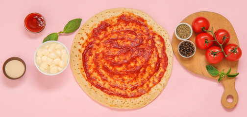 Pizza crust with tomato sauce and ingredients on pink background