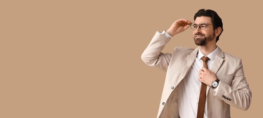 Handsome man in stylish suit on beige background with space for text