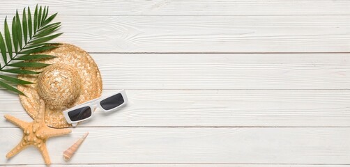 Summer composition with sunglasses and beach hat on white wooden background with space for text