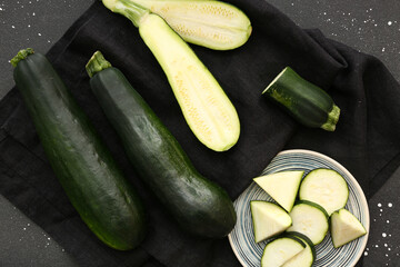 Fresh green zucchini and plate with slices on black background
