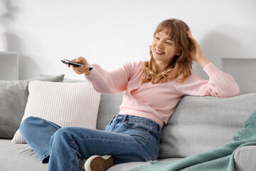 Young woman watching TV on sofa at home