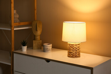 Beautiful glowing lamp on chest of drawers in interior of living room