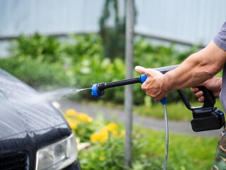 Man washing car using battery powered pressure washer