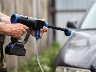 Man washing car using battery powered pressure washer
