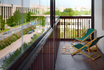 spacious and bright balcony with upholstered chairs, stylish and modern glazing, clear sunny weather