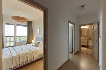 Cozy bedroom interior, beige bedspread and pillow, bedside lamp next to the bed, light from the window