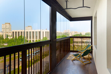 spacious and bright balcony with upholstered chairs, stylish and modern glazing, clear sunny weather