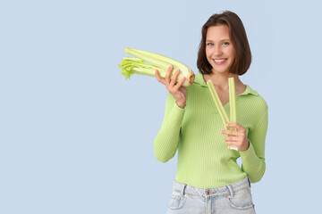 Beautiful young happy woman with fresh celery on blue background. Diet concept