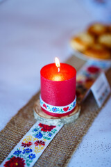 Traditional embroidered tablecloth with floral pattern, glass vase with wildflowers, and plate of pastries on a rustic celebration table.