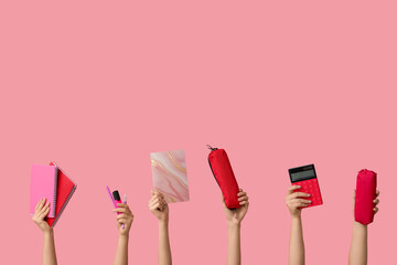 Female hands with different stationery on pink background