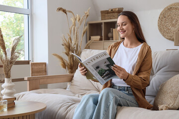 Young woman reading magazine on beige couch at home