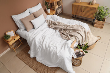 Interior of modern bedroom with big bed, commode and houseplants