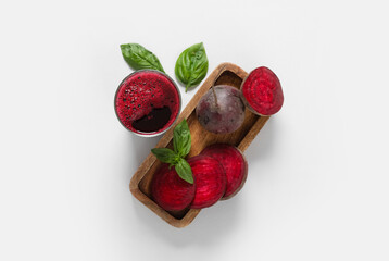 Glass of fresh beet juice with basil and vegetables on grey background
