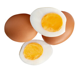 Top view of two raw chicken eggs and peeled cooked or boiled egg with egg yolk in two halves in stack isolated with clipping path in png file format