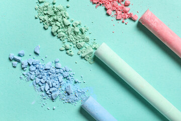 Colorful chalks with crushed pigments on turquoise background