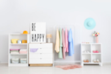 Blurred view of stylish dressing room with female clothes and poster