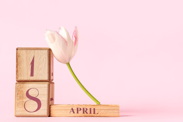 Cube calendar with date 18 April and beautiful tulip flower on pink background
