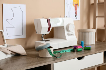 Box with tape measure and thread spools on tailor's table in atelier, closeup