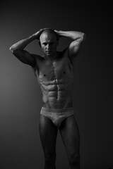 Naklejka premium Athletic man showcasing a powerful physique in a stunning black and white portrait, emphasizing strength and confidence in a minimalist style.