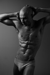 Fototapeta premium Black and white portrait of a man showcasing a strong physique, exuding confidence and strength in a dynamic pose with dramatic lighting.