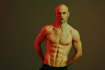 Strong man posing confidently, showing toned physique in a dramatic light setting. The composition...