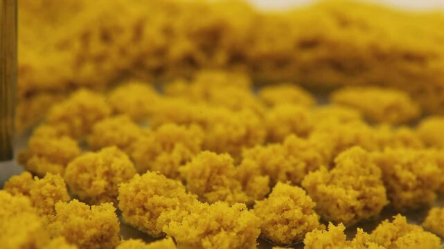 Bright yellow kinetic sand being manipulated with a grid patterning tool. The smooth texture transforms as the tool creates geometric impressions, then returns to its soft, flowing surface texture.