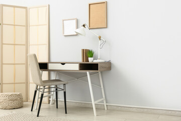 Interior of office with folding screen, workplace and blank frames