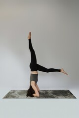 Woman Balancing in Headstand Yoga Pose on Tie-Dye Mat – Strength, Focus, and Control in...