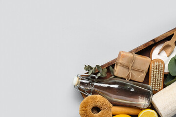 Wooden basket with natural products and supplies for cleaning on grey background