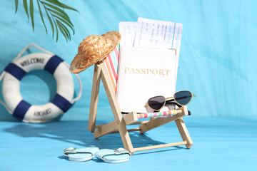 Small deckchair with beach accessories, passport and tickets on color background