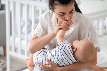 Beautiful young happy mother with her cute little daughter sitting on bed at home