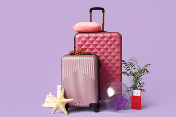Stylish suitcases, beach accessories, passport, ticket and decor on lilac background