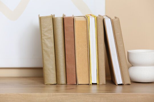 Different books and decor on wooden table near color wall