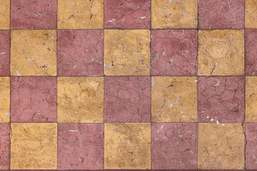 Piso cuadriculado decorado en contraste de amarillo con rojo. Loseta desgastada y vieja. Detalle...