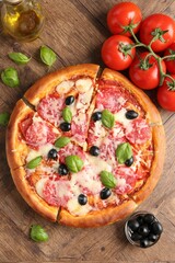 Tasty pizza and ingredients on wooden table, flat lay
