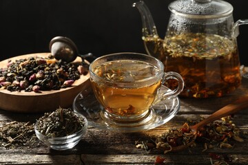 Refreshing herbal tea and dry leaves on wooden table, closeup