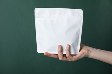 Woman with zipper stand-up pouch on green background, closeup. Mockup for design