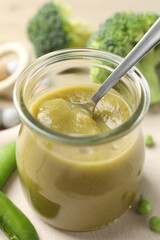 Baby food. Tasty puree in glass jar and ingredients on table, closeup