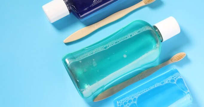 Different oral care products on light blue background, flat lay. Camera moving down