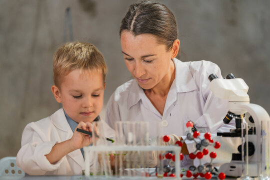 A female scientist teaching a young boy about science in a modern lab. Inspiring the next generation through STEM education, scientific curiosity, and hands on experiments in chemistry and biology.