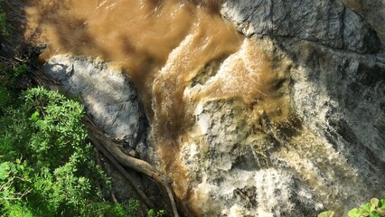 From above, a drone captures a powerful flood flowing through lush forest, illustrating the resilience and complexity of rainforest ecosystems and their role in nature. Thailand.
