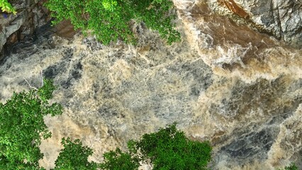 From above, a drone reveals turbulent river waters weaving through rocky terrain, framed by dense...