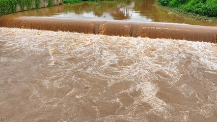 From above, floodwaters flow turbulently, carrying sediment and debris downstream, illustrating the...