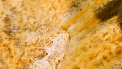 Overhead view reveals chaotic floodwater currents full of silt, illustrating the intense force and environmental influence of natural flooding on soil and waterways.
