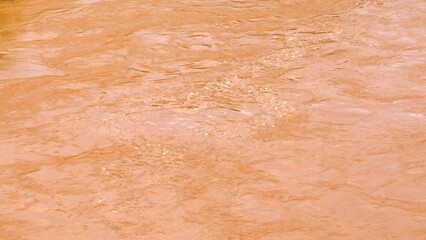 Aerial view shows muddy floodwater surface glistening under sunlight, capturing the interplay of...