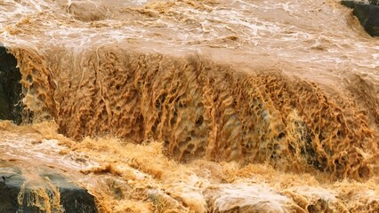 Bird’s eye drone image of churning muddy floodwaters shows the direct effects of global warming...